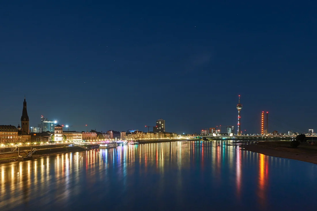 Düsseldorfer Rheinufer mit Schlossturm, Rheinturm und Rheinkniebrücke zur blauen Stunde.