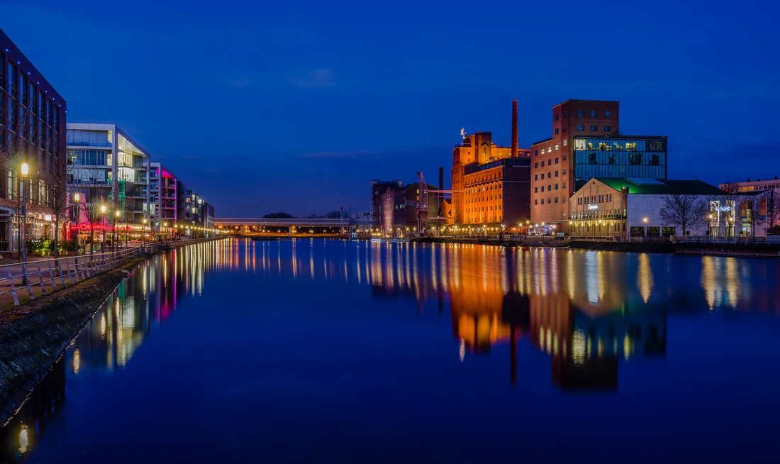 Duisburger Innenhafen mit beleuchteten Gebäuden zur blauen Stunde.