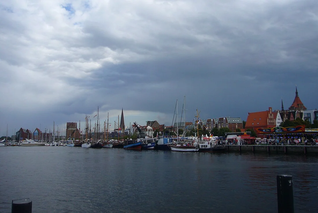 Blick über den Rostocker Stadthafen mit Segelbooten und Kirchtürmen der Altstadt.